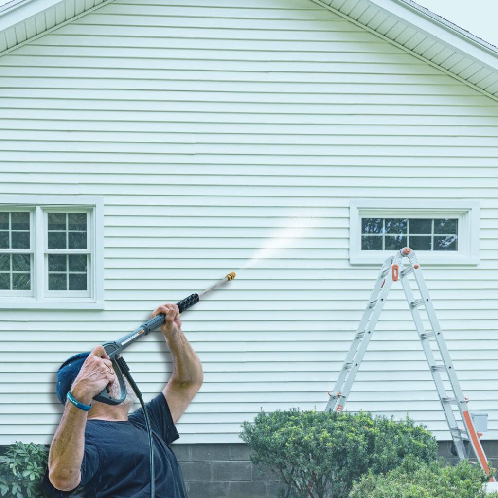 homeowner pressure washing siding as part of annual maintenance