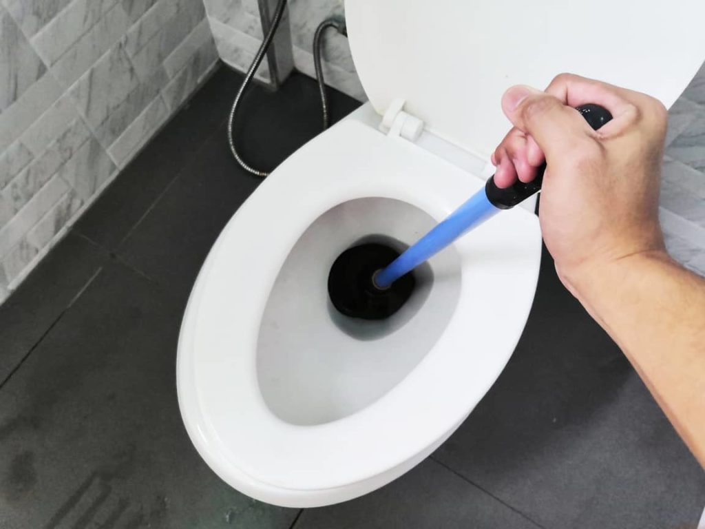 Using a plunger to unclog the toilet.